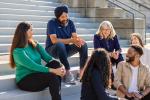 CEO Aman Bhutani shown with a group of people chatting on steps outside of a building.
